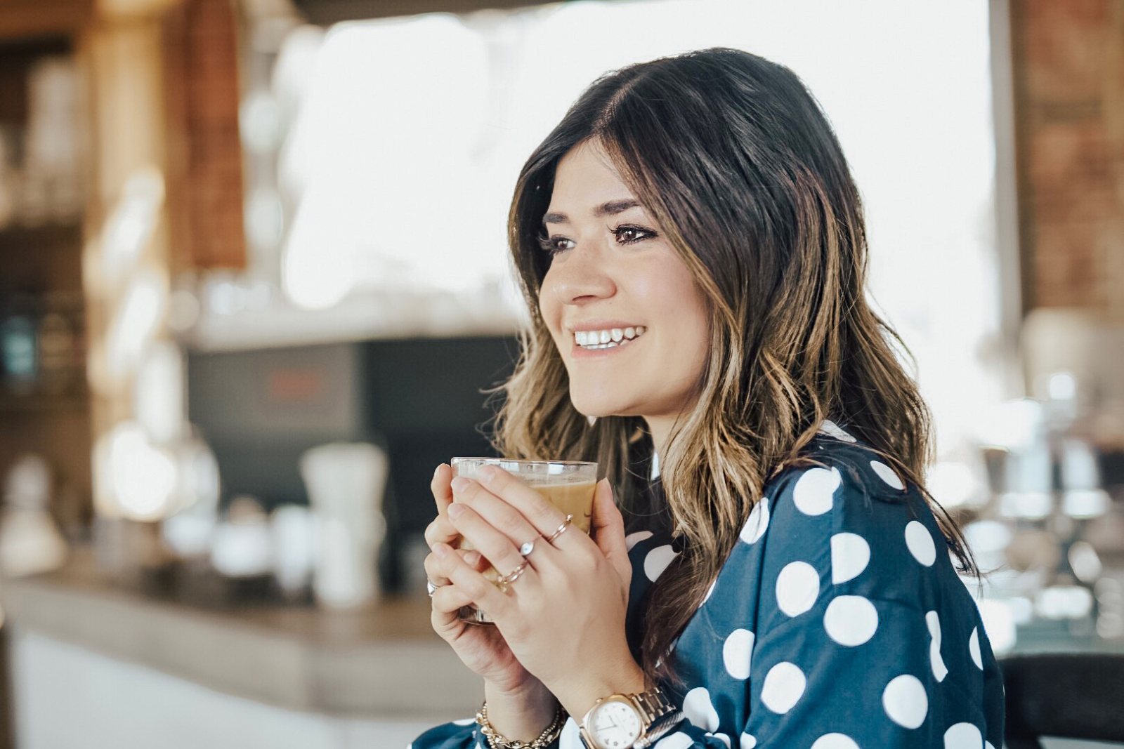 Carolina Hellal from Chic Talk wearing a polka dot blouse and jeans while enjoying an iced-coffee at Steam Espresso Bar - STEAM ESPRESSO BAR DENVER by popular Denver blogger Chic Talk