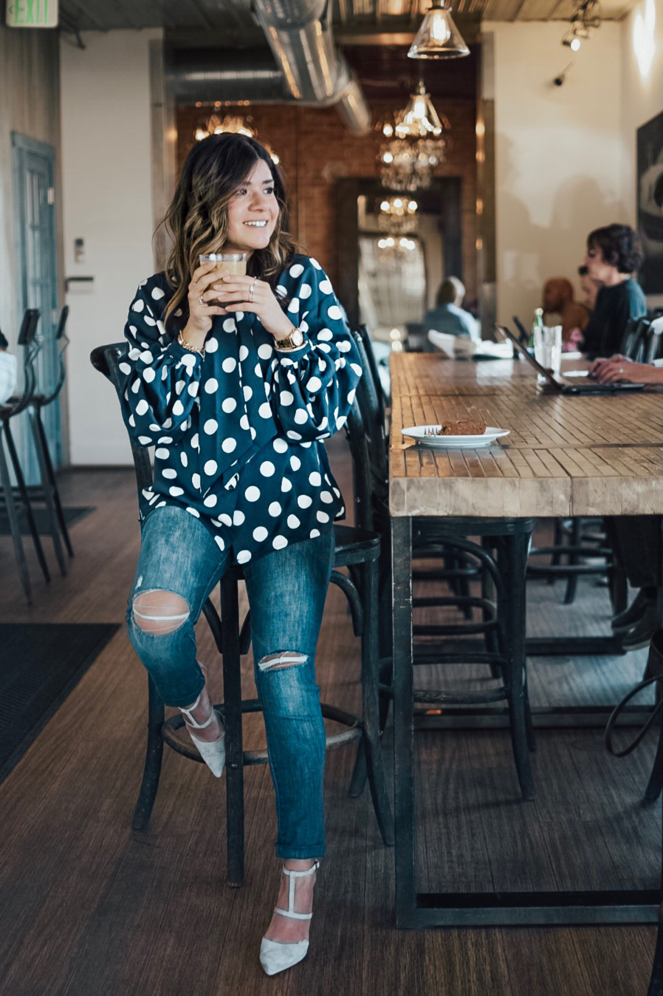 Carolina Hellal from Chic Talk wearing a polka dot blouse and jeans while enjoying an iced-coffee at Steam Espresso Bar - STEAM ESPRESSO BAR DENVER by popular Denver blogger Chic Talk