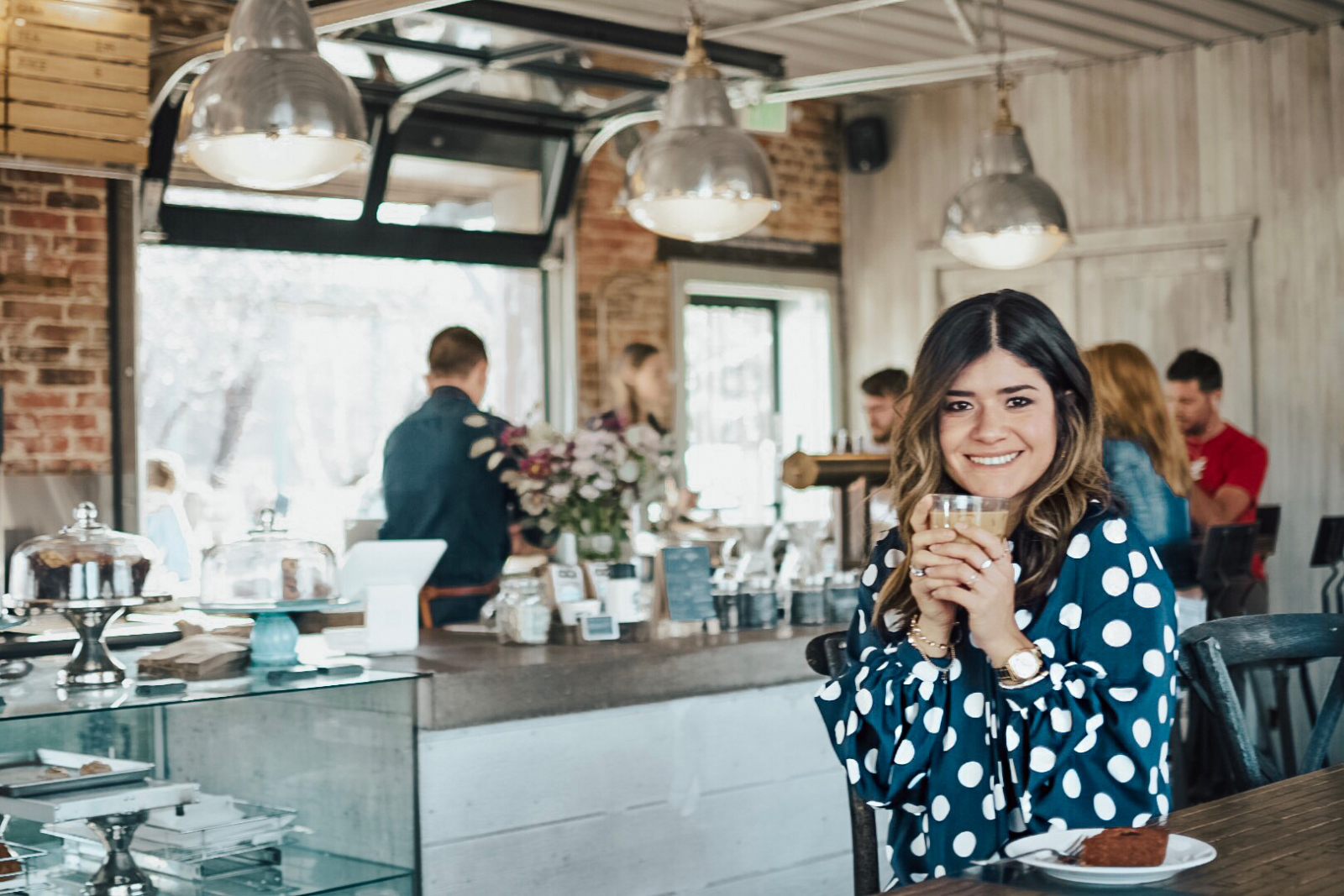Carolina Hellal from Chic Talk wearing a polka dot blouse and jeans while enjoying an iced-coffee at Steam Espresso Bar - STEAM ESPRESSO BAR DENVER by popular Denver blogger Chic Talk