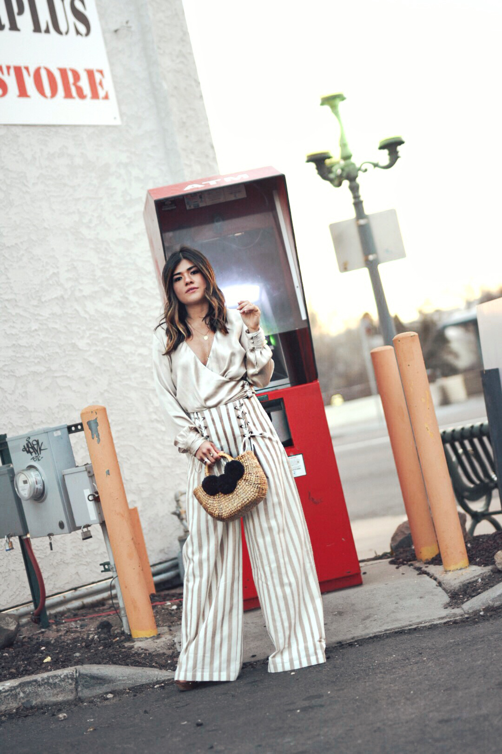 Carolina Hellal wears the Chriselle Lim x J.O.A wide leg pants, h&m silk top and JADEtribe mini pom pom bag - STYLING WIDE LEG PANTS FOR SPRING by popular Denver fashion blogger Chic Talk